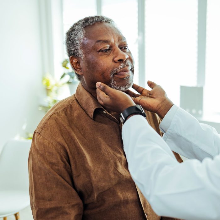 Doctor doing throat examination on older man