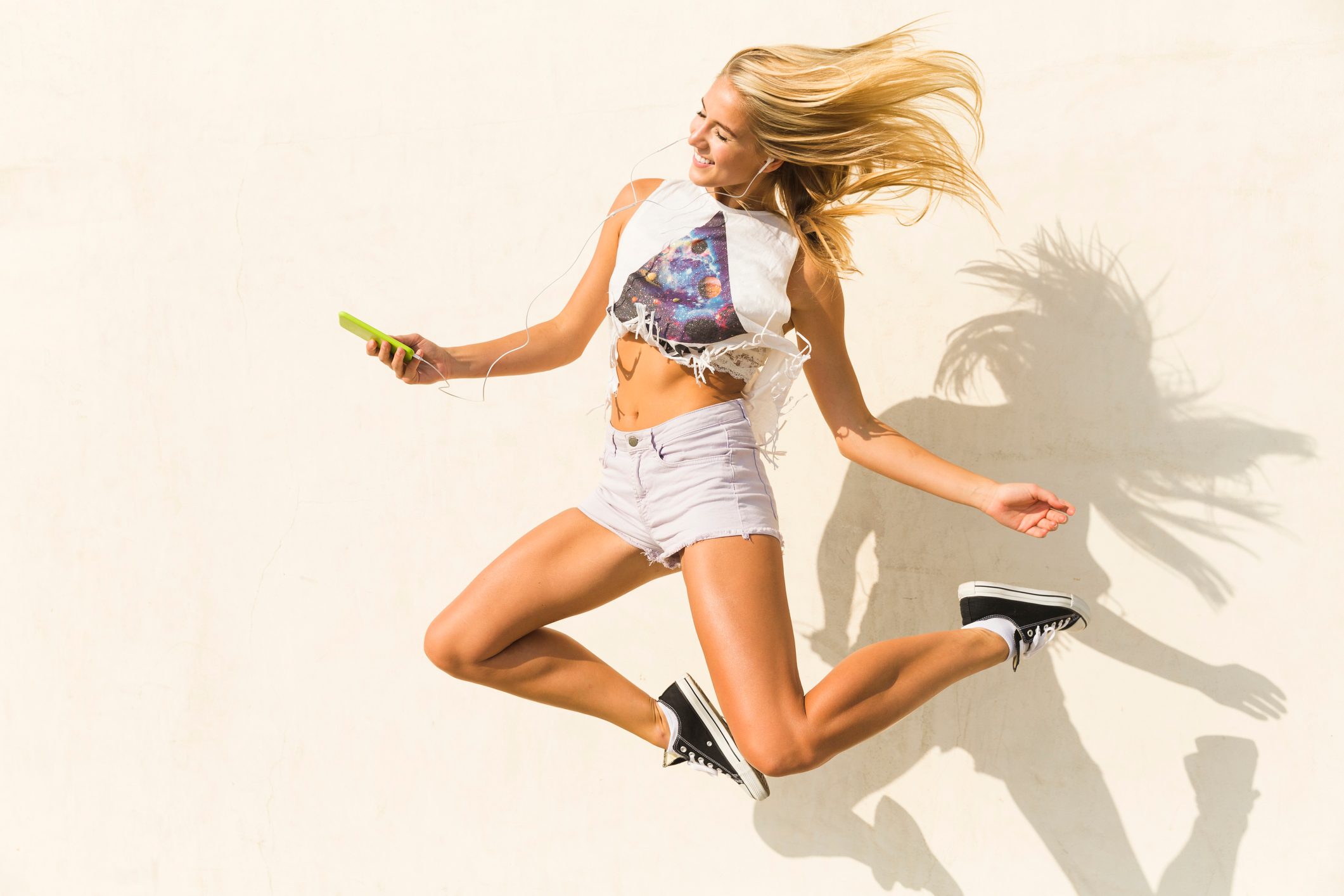 Carefree woman jumping in front of wall