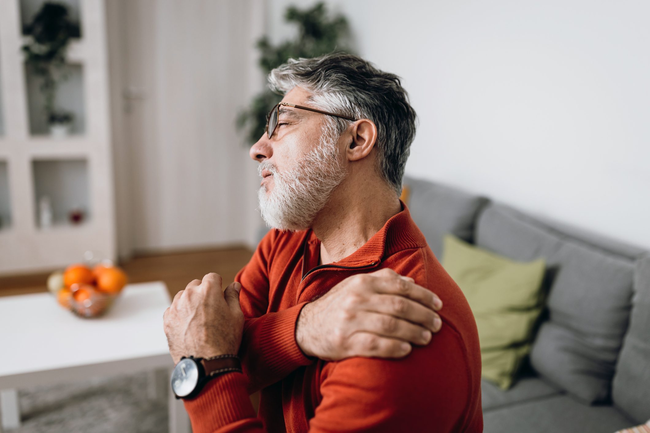 man holding his sore and sprained shoulder from walking dogs