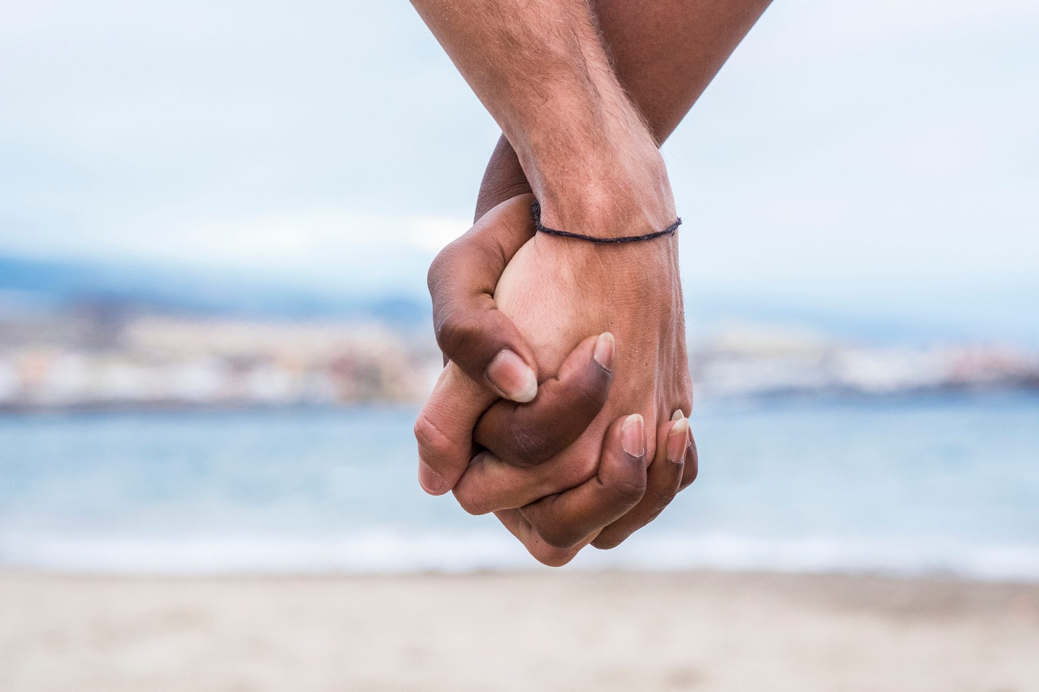 Close-up of two hands connected on the beach