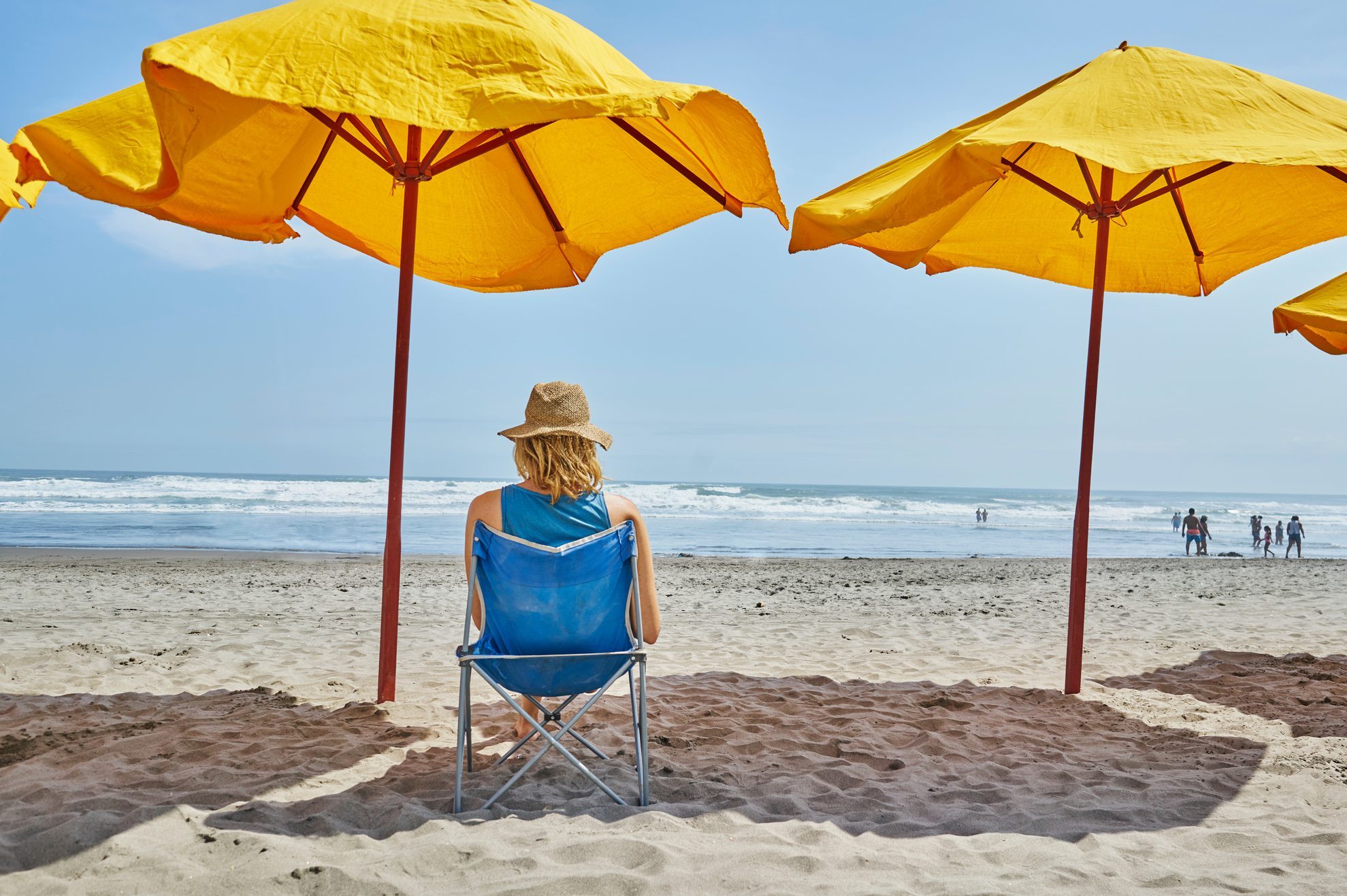 Rear view of female tourist sitting under beach umbrella, Camana, Arequipa, Peru