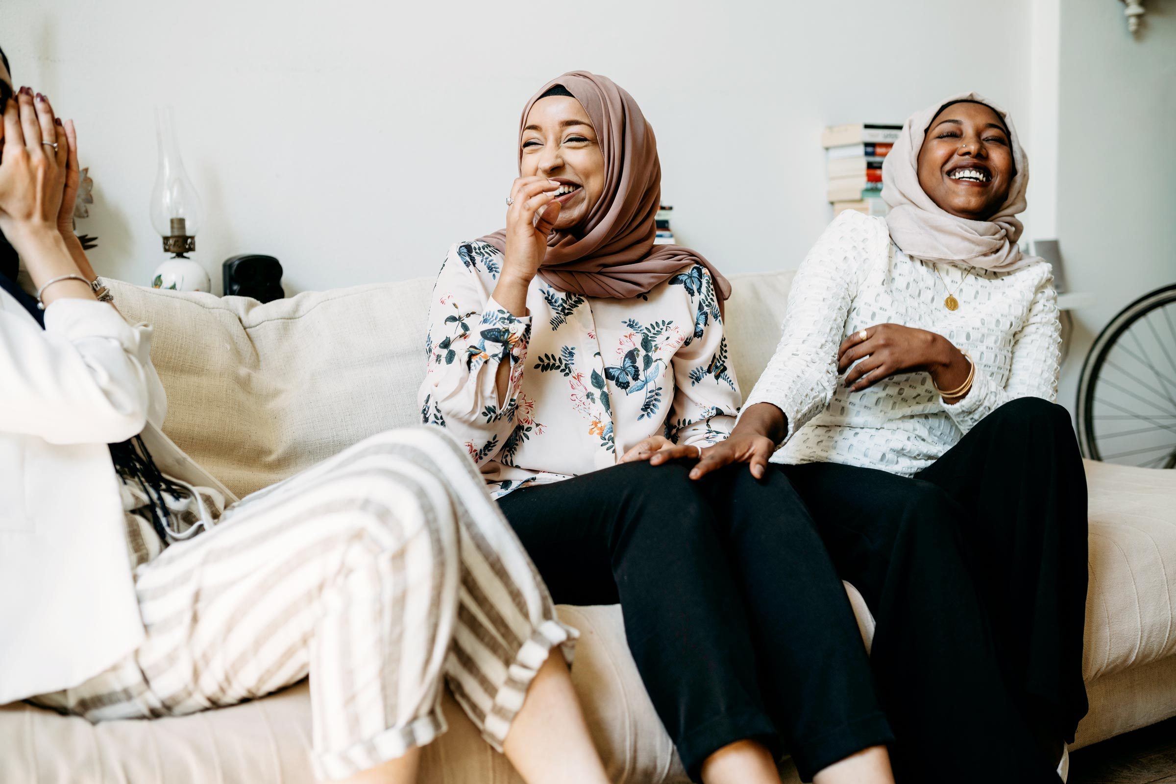 Three friends talking together sitting on the sofa at home