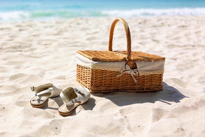 picnic basket and candles on the sand at the beach