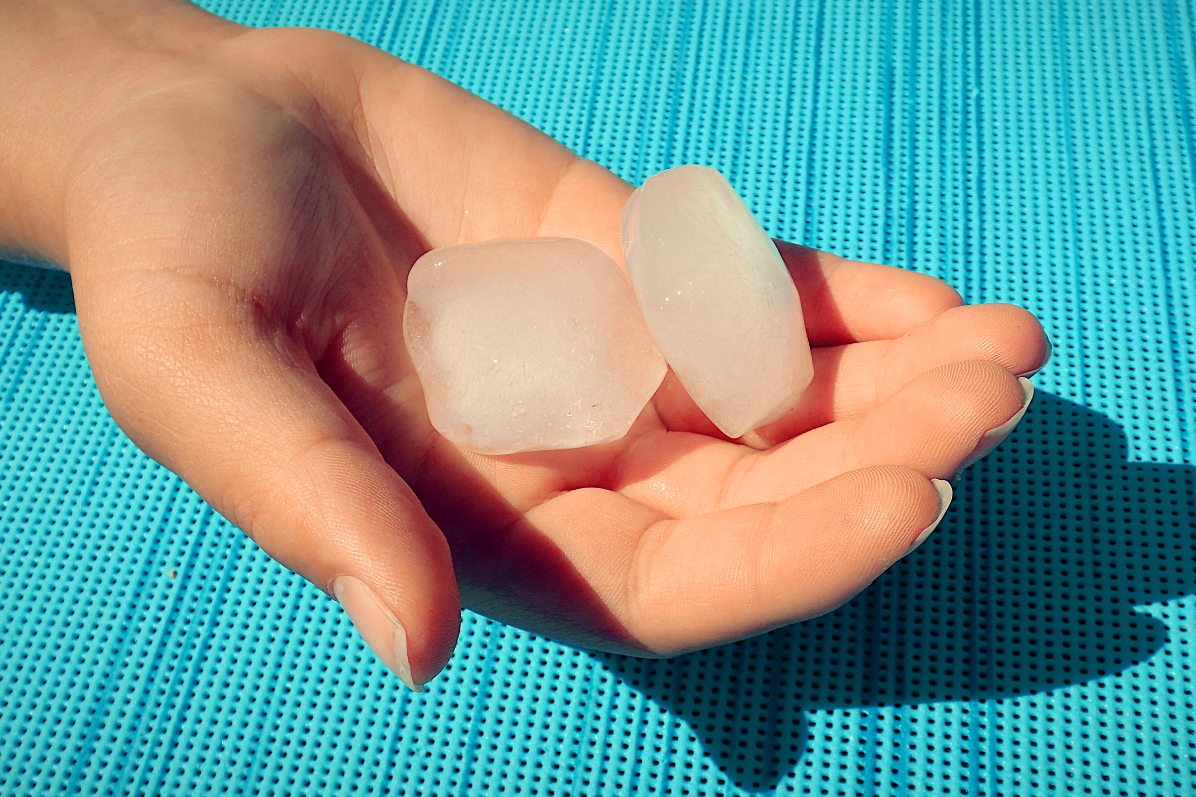 hand holding two ice cubes to For Temperature Play During Sex In The Summer