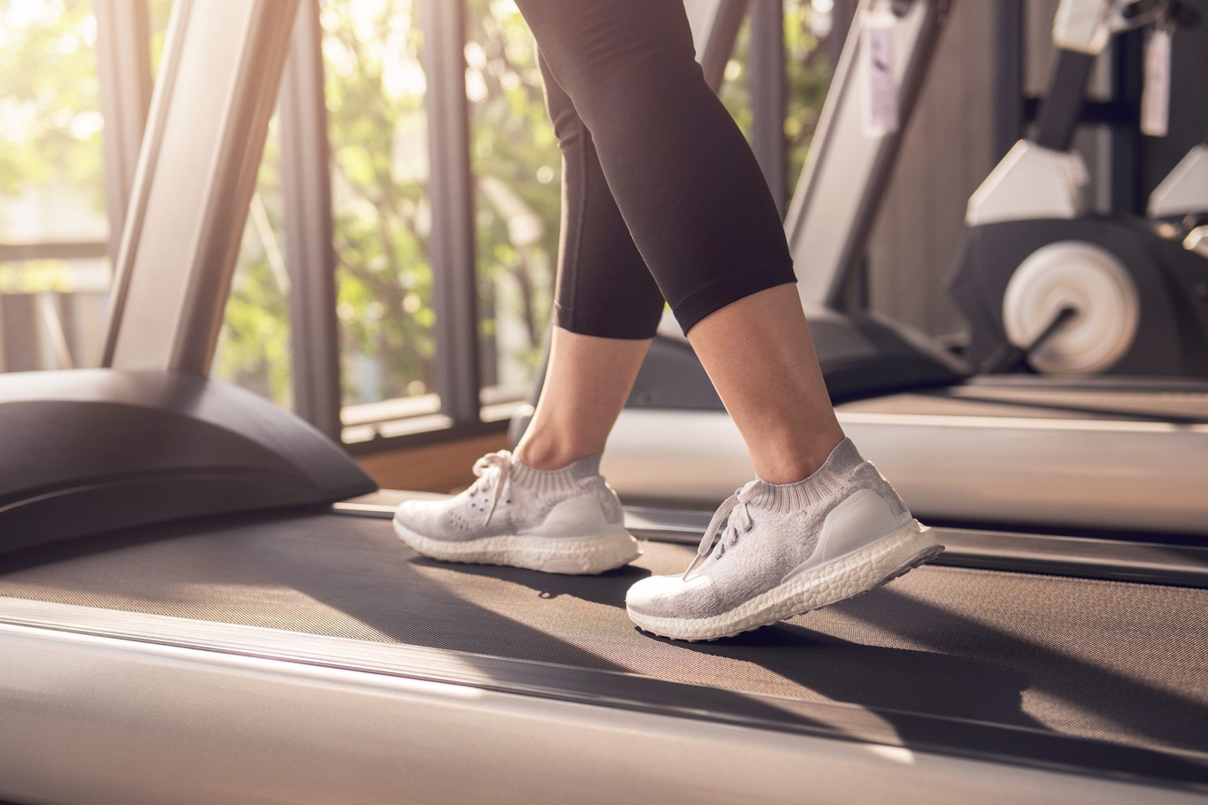 Woman running in machine treadmill at fitness gym at morning.