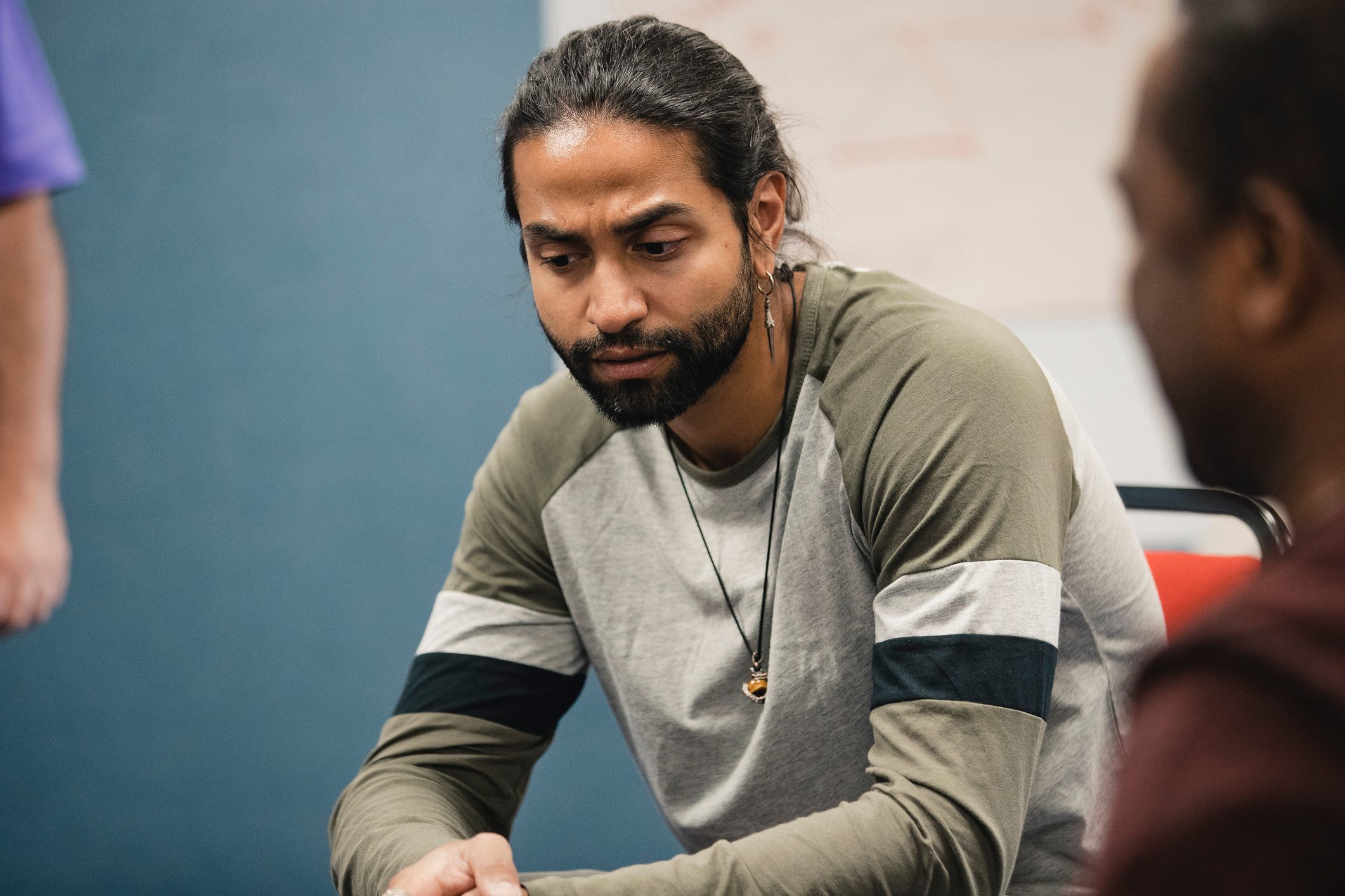 Mid-adult man is sitting in a mental health support group deep in thought.