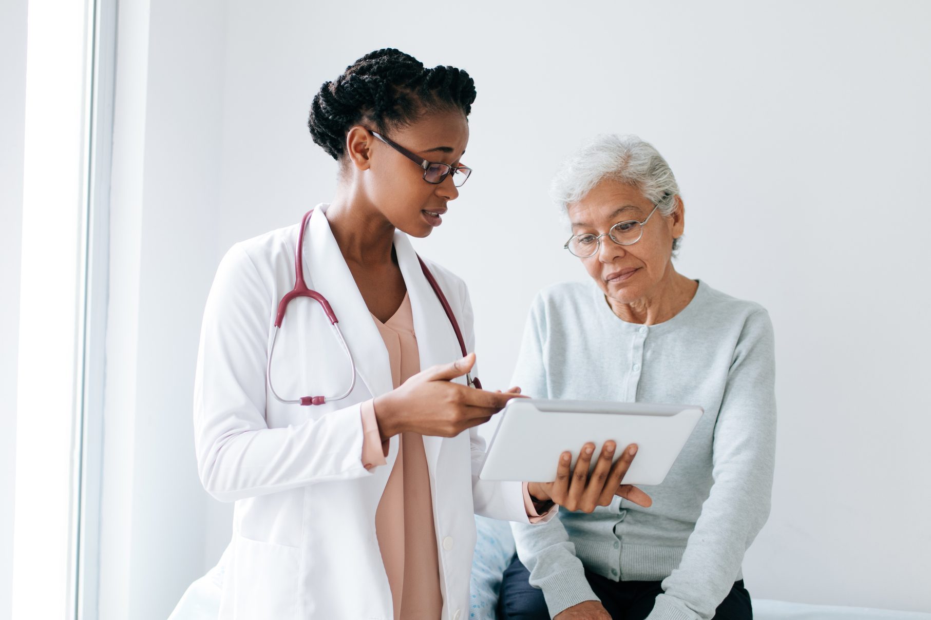 Black female doctor showing digital tablet to senior patient