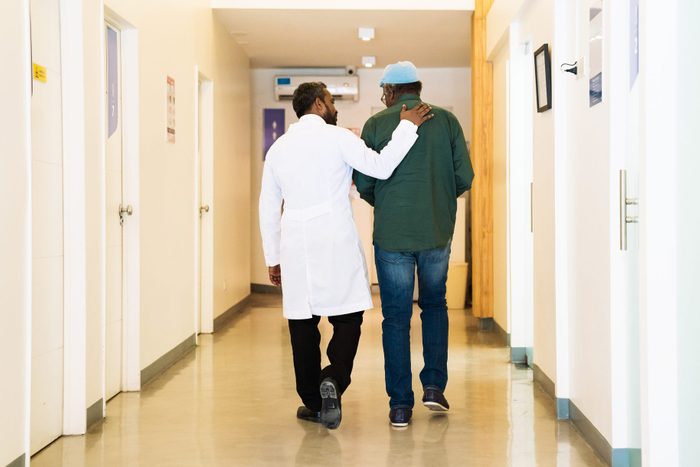 Rear view of doctor with patient in corridor