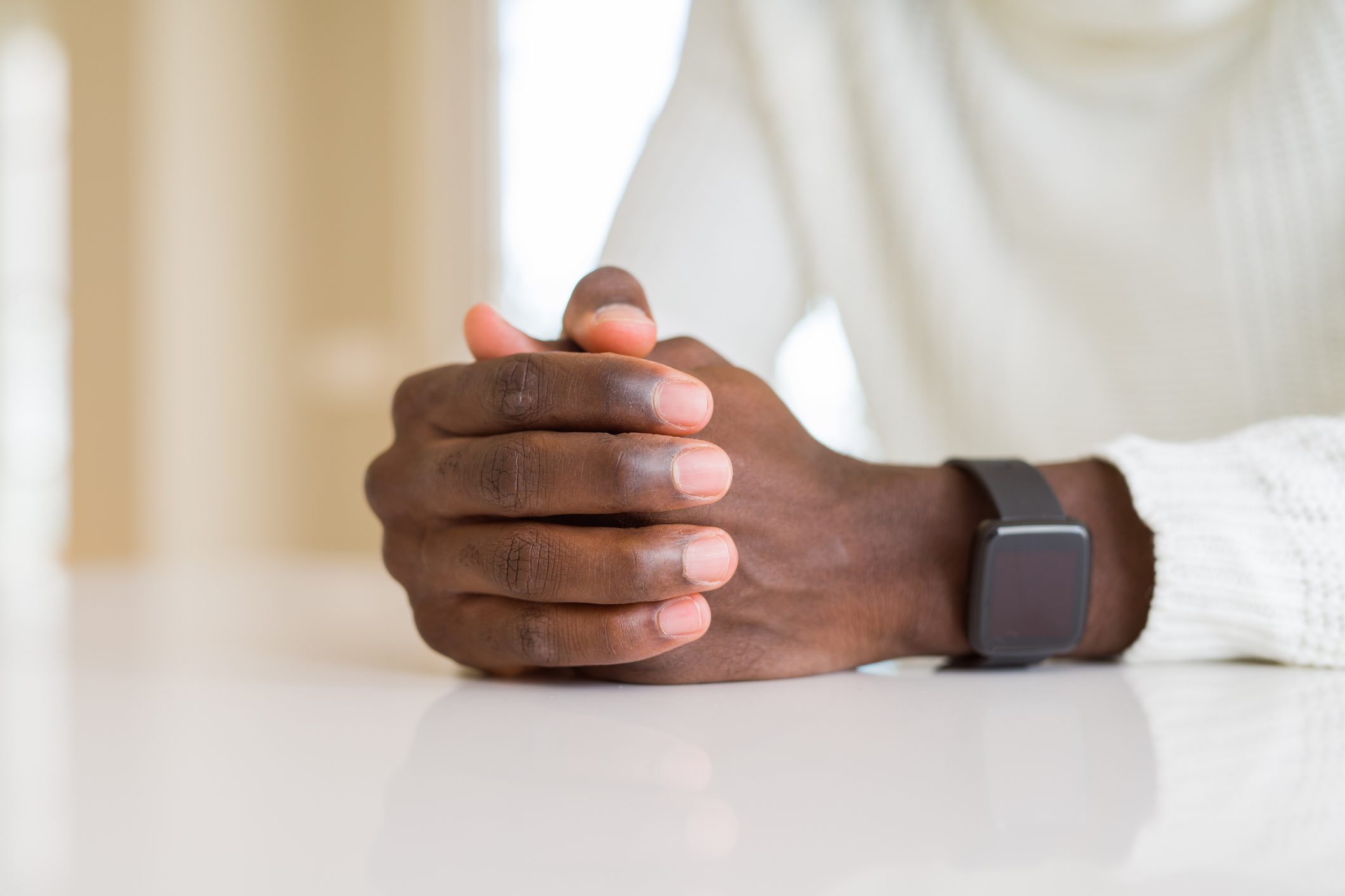 Close up of crossed hands of african man over table
