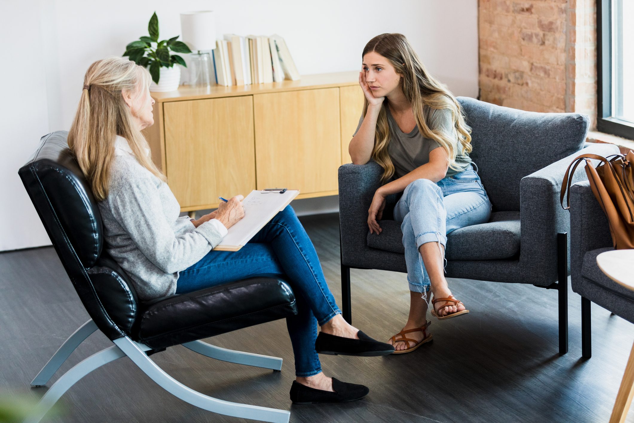 Young woman cries as therapist watches with empathy