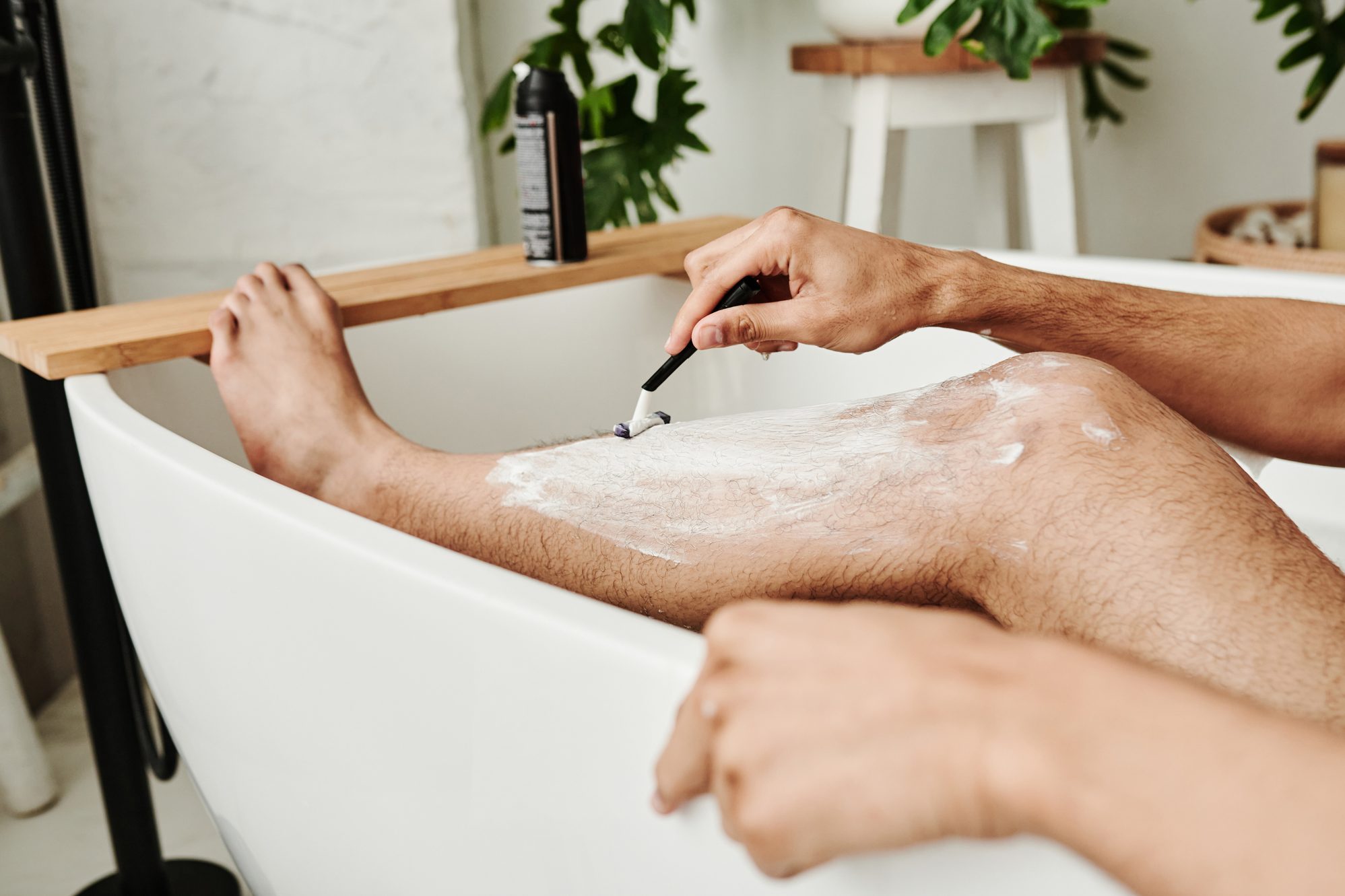 Man shaving his leg in bathroom