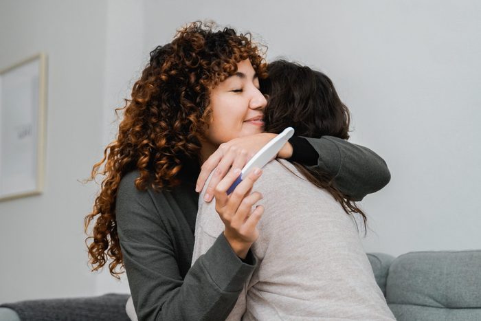 Gay female fertility: Lesbian couple celebrating with pregnancy test at home - Soft focus on expecting mother face - Lgbt diversity concept
