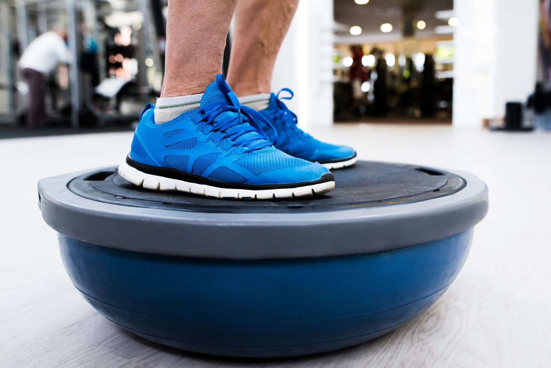 Unrecognizable senior man in gym standing on bosu balance ball