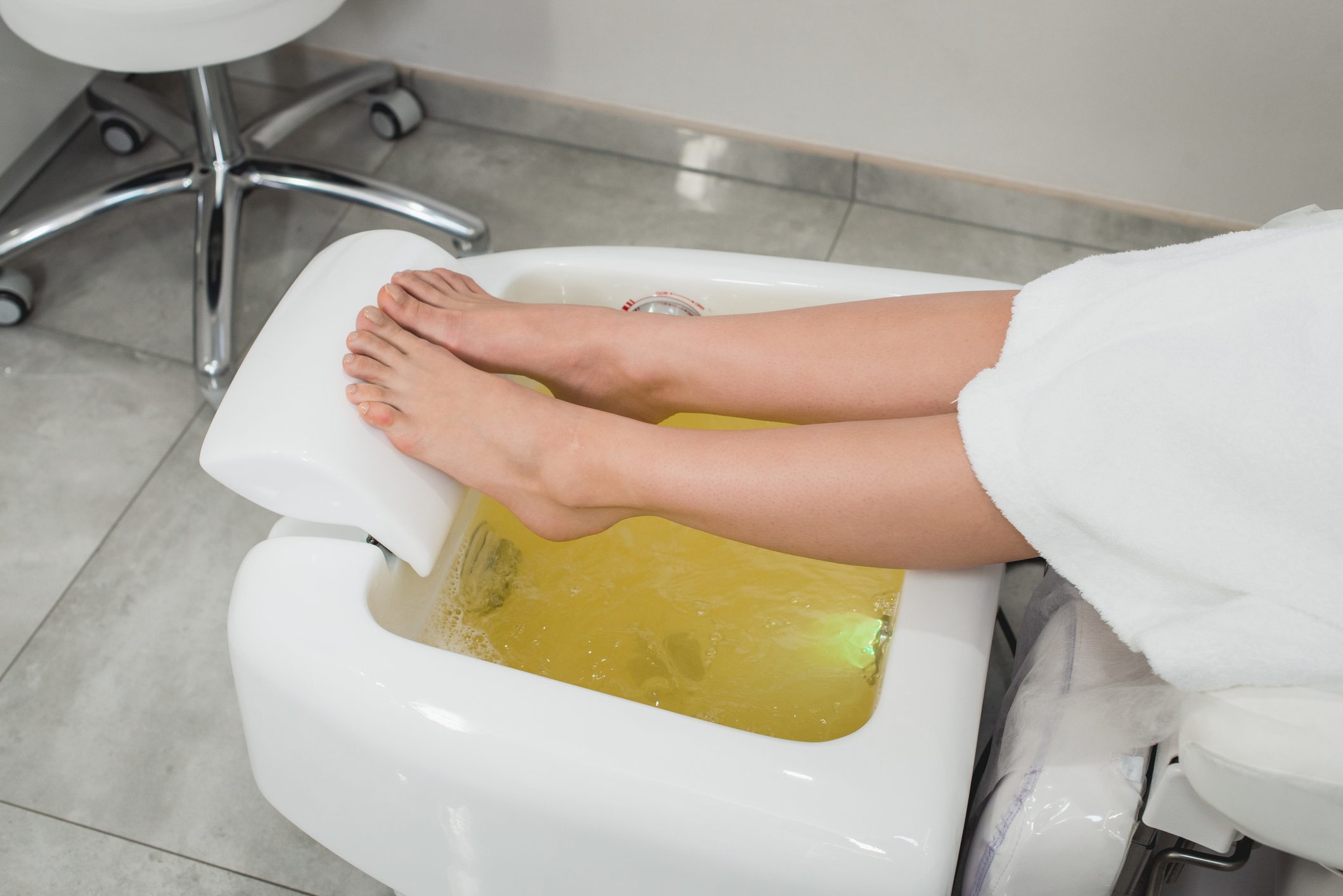 beautiful legs of a girl in a white bathrobe. modern beauty salon