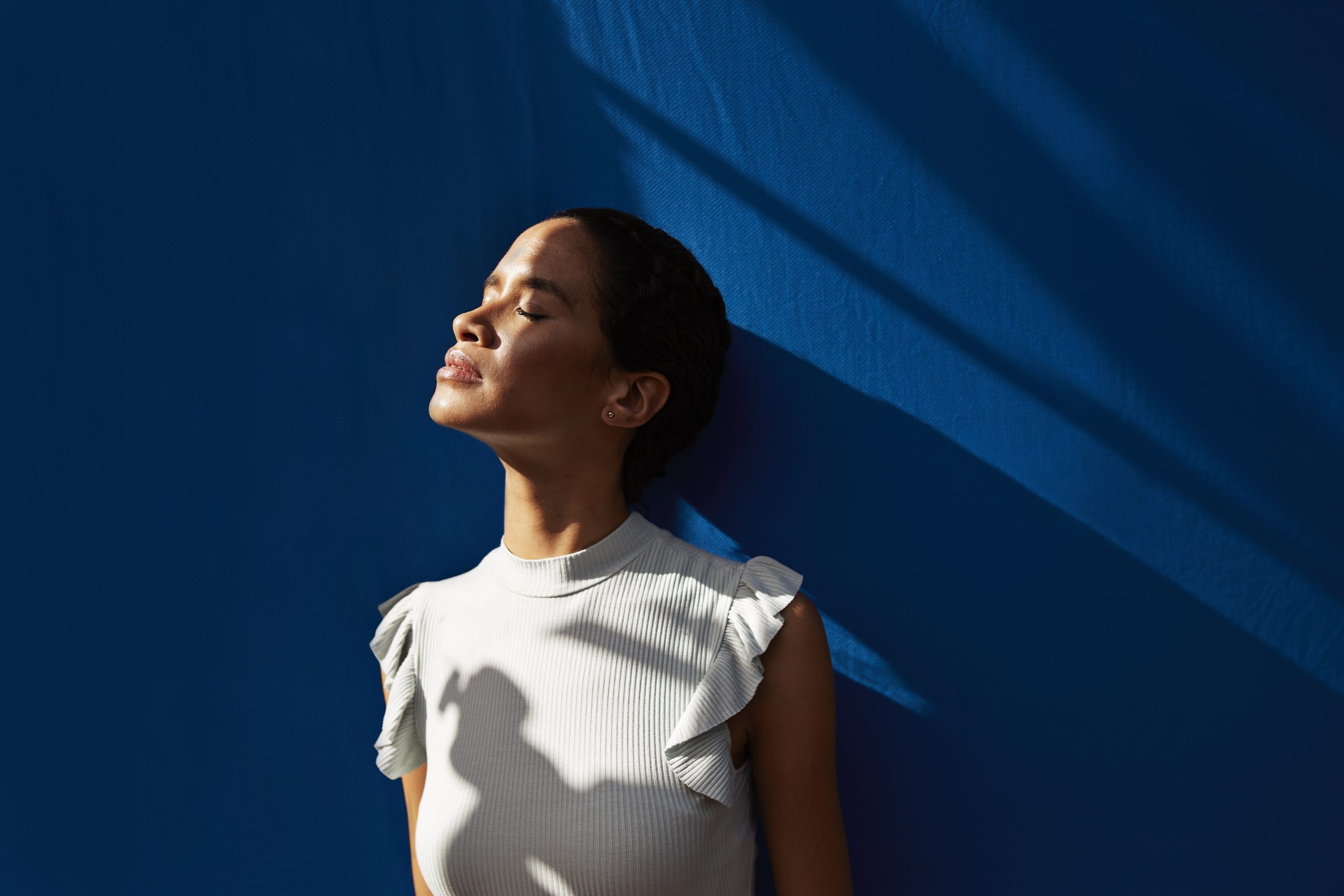 Thoughtful Woman Standing Against Blue Wall