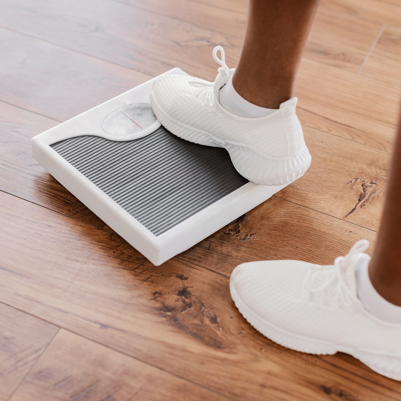 Closeup of African Woman Standing On Scales. Slimming Concept