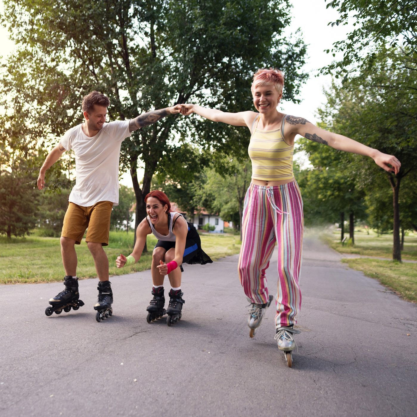 Smiling friends having fun roller skating in the park