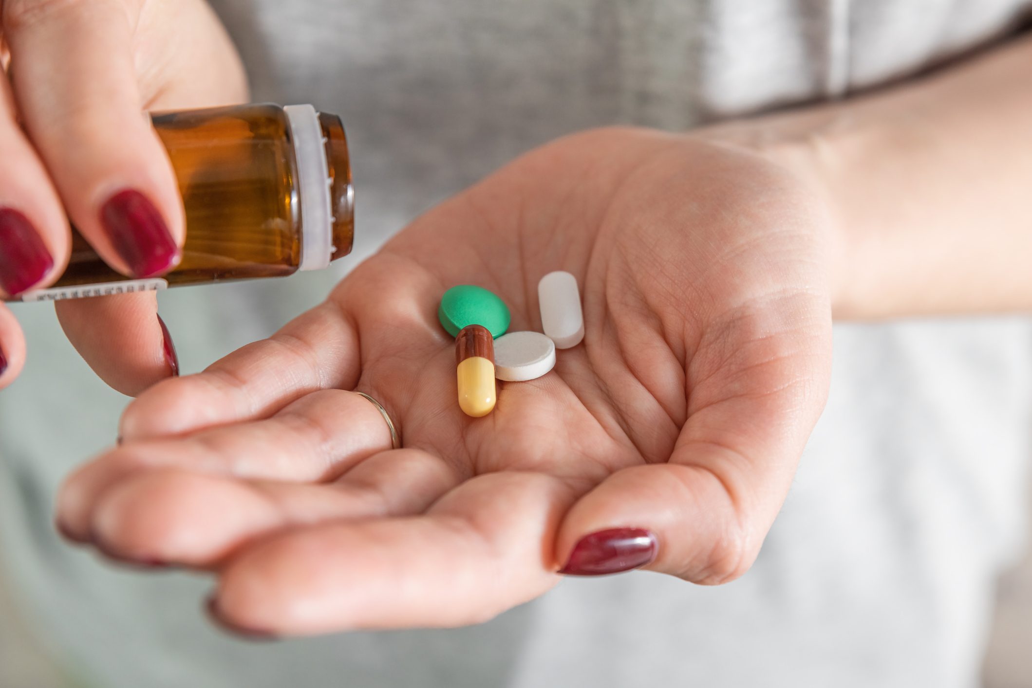 Woman taking various medicine pills and tablets. Dose of drugs for course of treatment in female palm. Close up