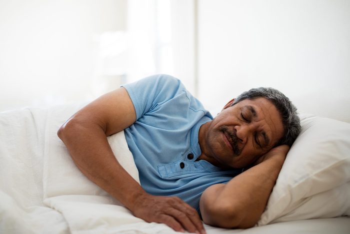 Senior man resting on bed in bedroom