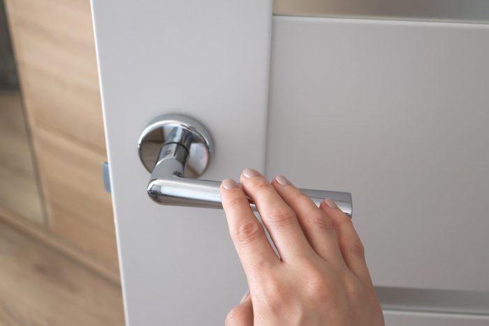 Female hand on metal door handle. Modern interior detail