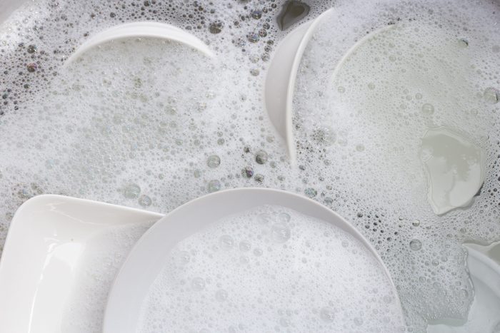 Washing dishes, Close up of utensils soaking in kitchen sink.