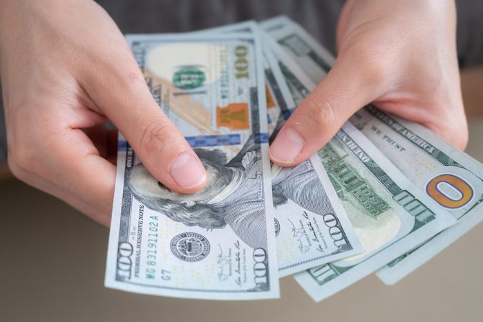Close up of someone hands holding and counting American dollar banknotes in her hand.