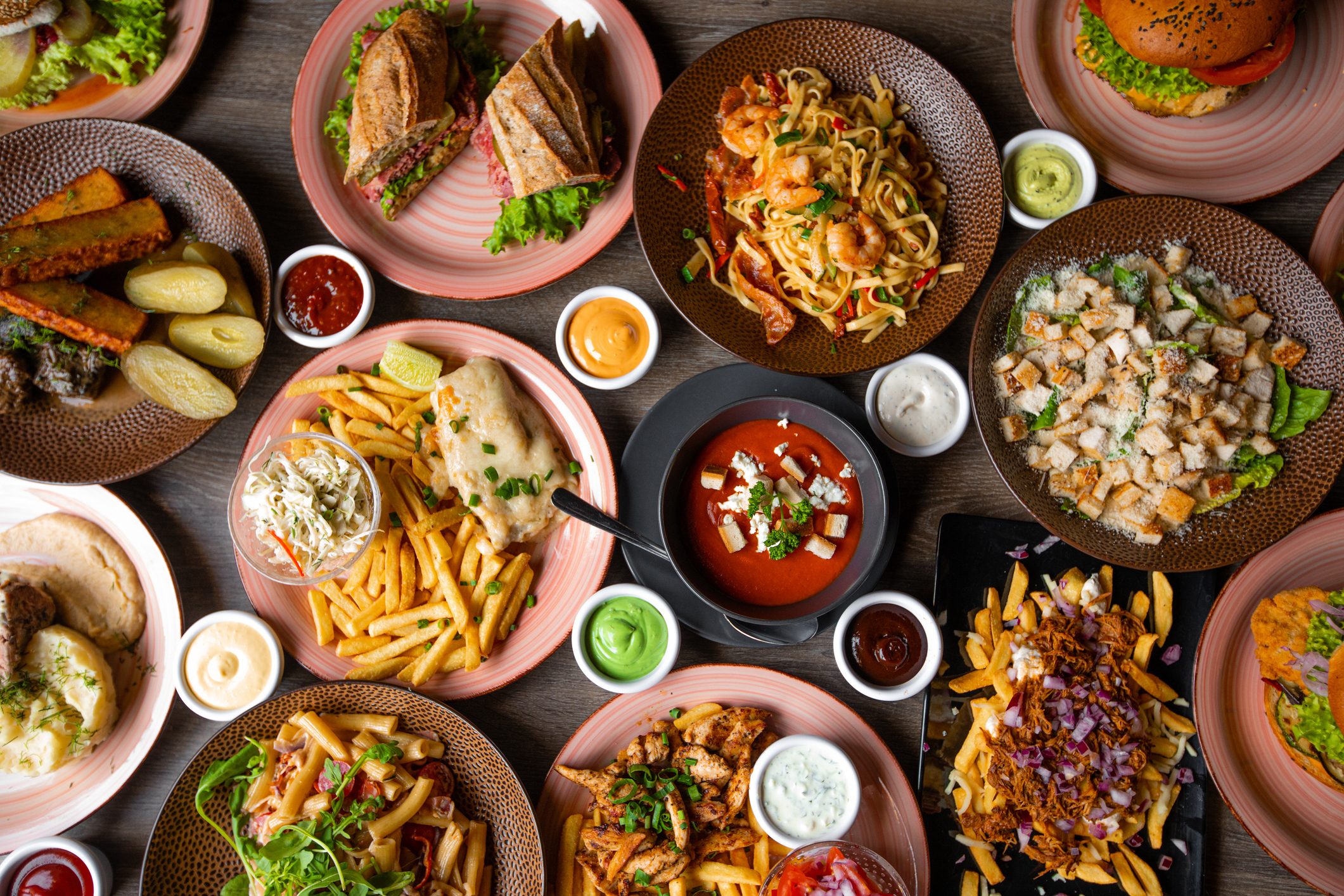 Snack, junk, fast food on table in restaurant. Soup, sauce ornament, grill hamburger, french fries, pasta with sea food