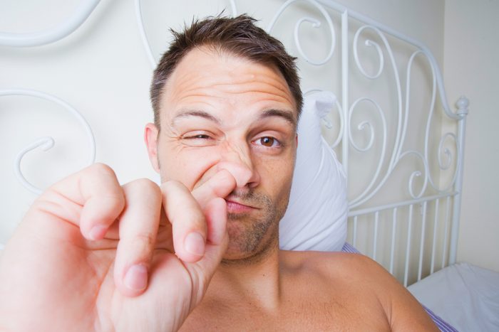 Man picking his nose in bed.