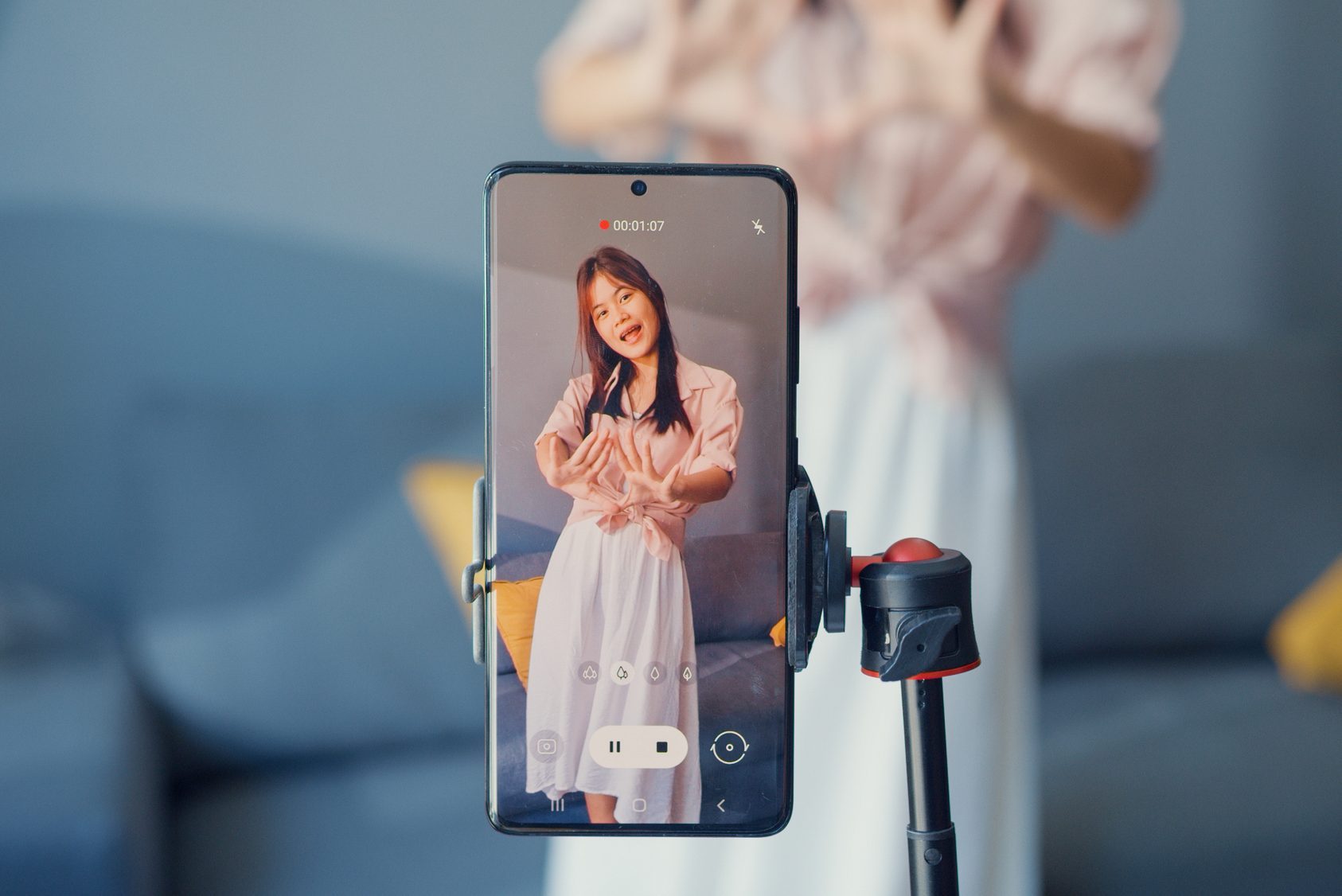 Happy young Asian girl blogger front of phone camera record video enjoy with dance content in living room at home. Social distance coronavirus pandemic concept. Freedom and active lifestyle concept