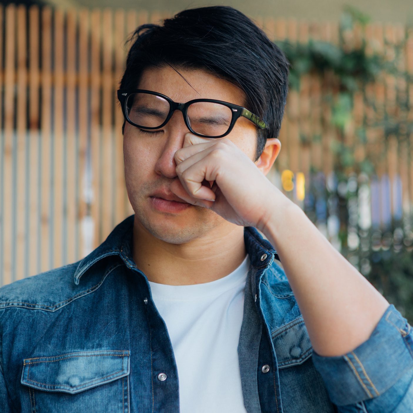 Young Man Rubbing Eye With Hand
