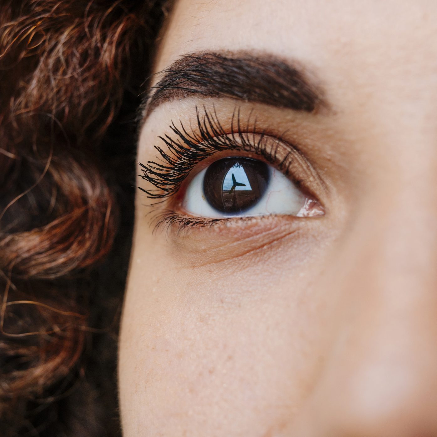 Windmill reflecting on eyeball of thoughtful woman