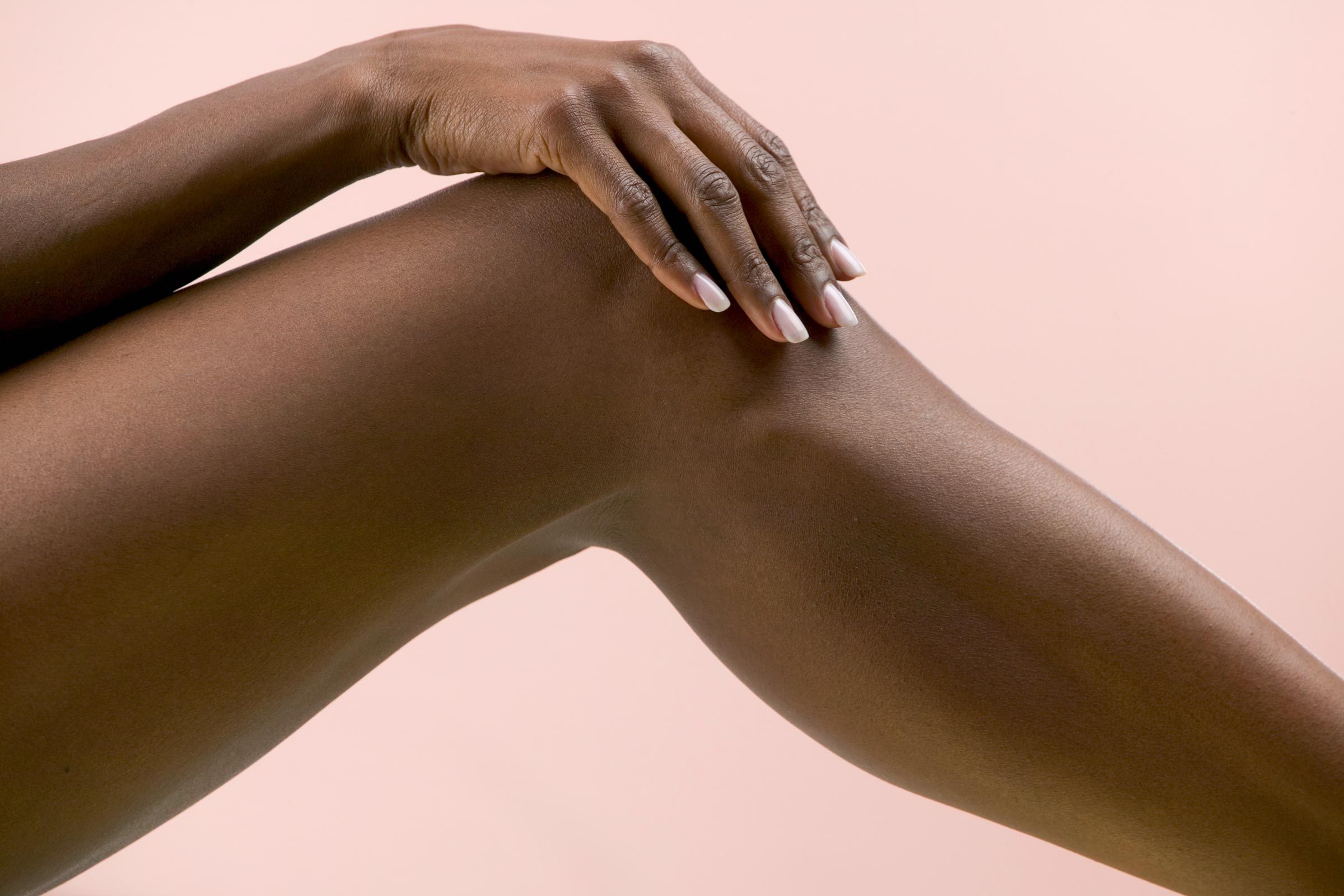 woman's hand and knee on a pink background