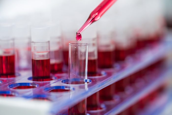 Scientist hand holding test tube with blood in laboratory.