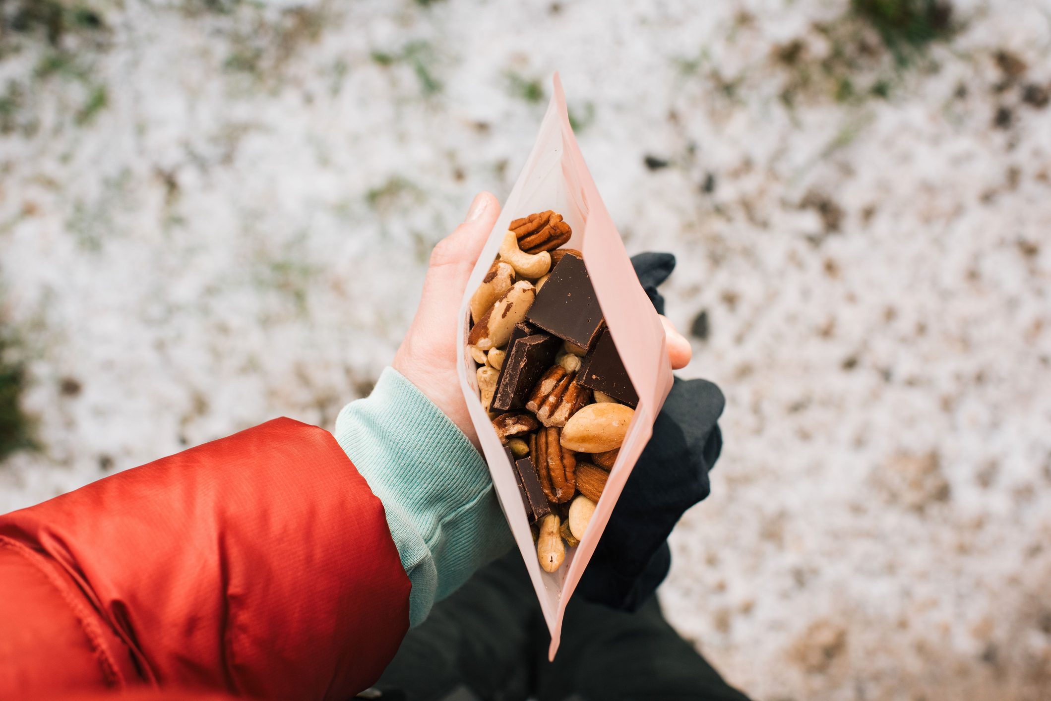 woman holding trail mix in a reusable snack bag whilst hiking