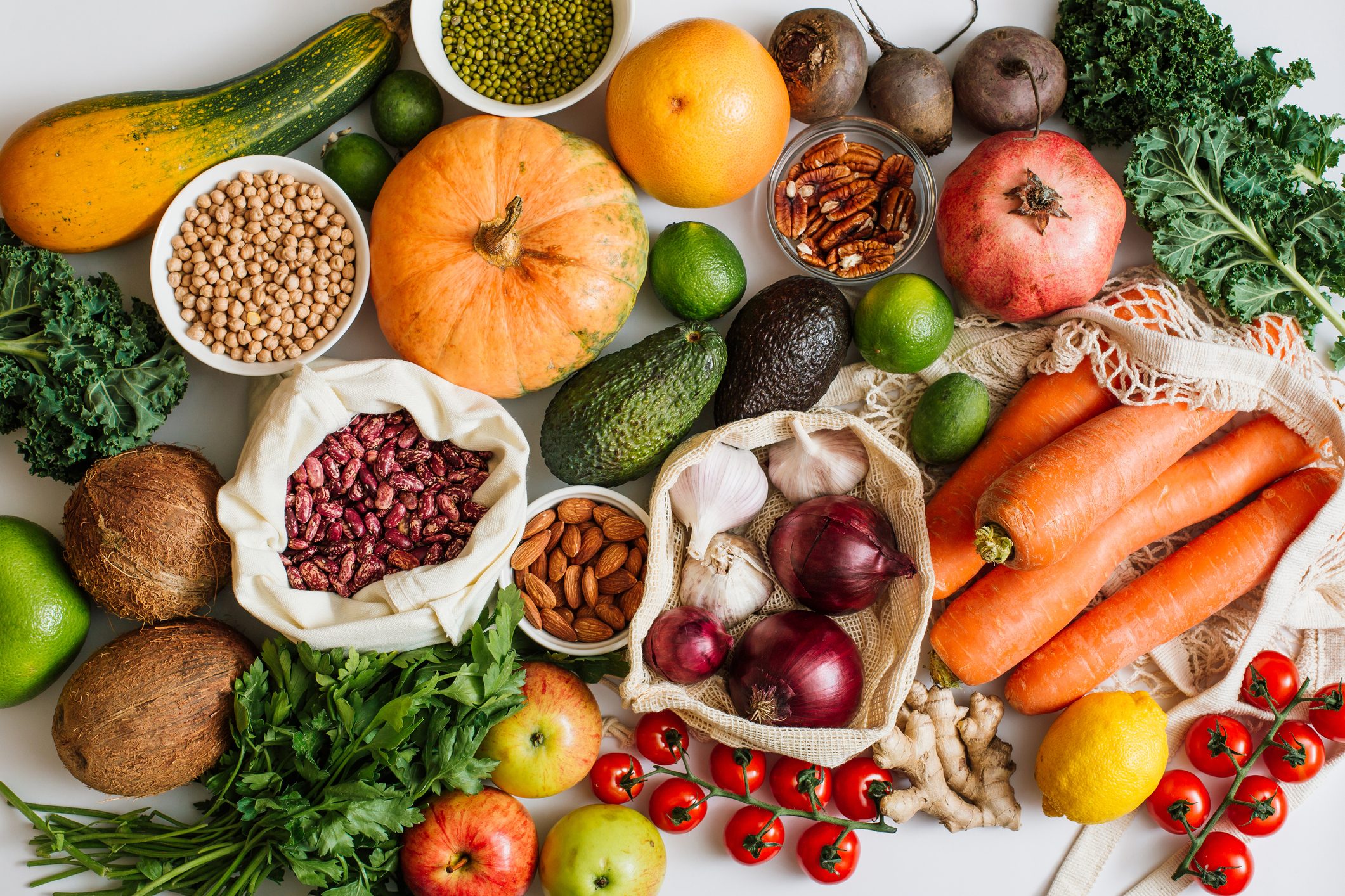 Variety Fresh of organic fruits and vegetables and healthy vegan meal ingredients in reusable eco cotton bags on table. Zero waste shopping concept. Healthy food, clean eating, eco friendly, no plastic. Flat lay, top view