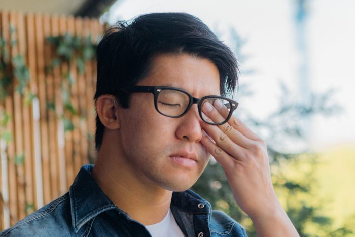 Young Man Rubbing Eye With Hand