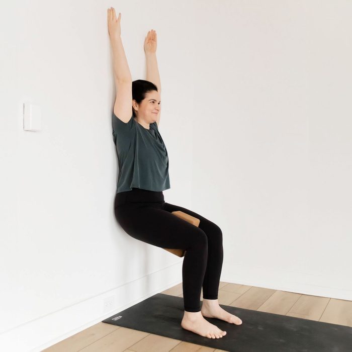 Supported chair pose at the wall