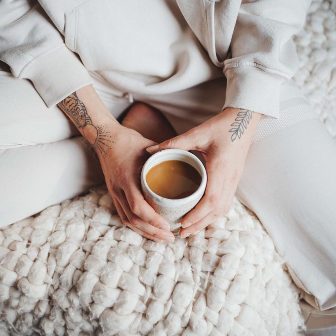 hands holding mug of MUDWTR in a bed