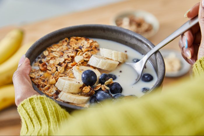 Happy young girl eating a healthy oat meal breakfast