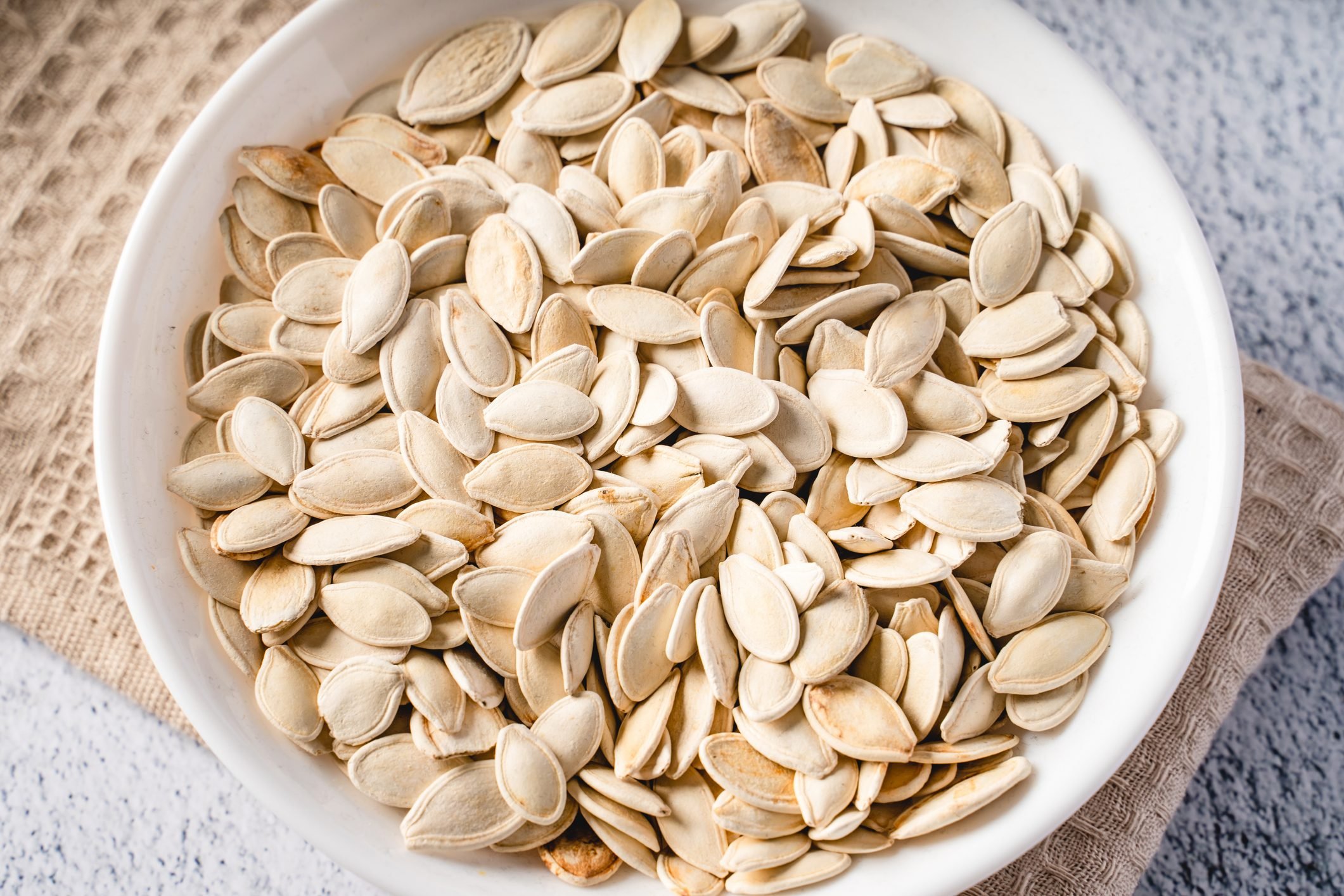 Top view on fresh salted roasted pumpkin seeds in bowl on table