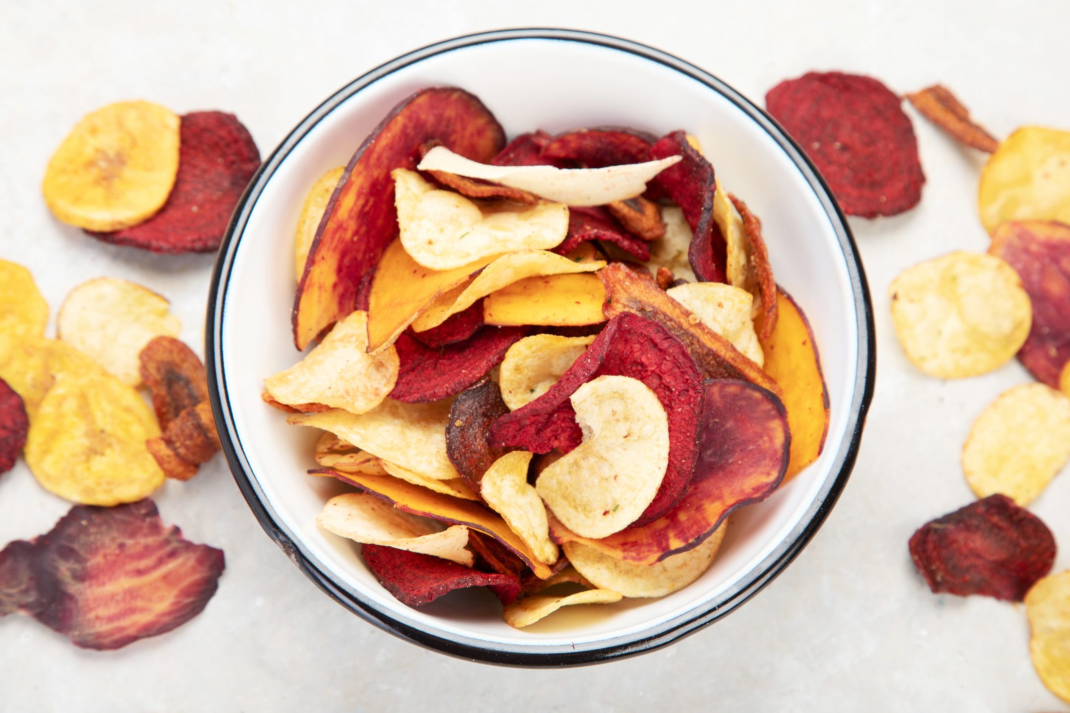 Vegetable organic chips made from potatoes, beets and carrots in a white plate for a snack, top view.