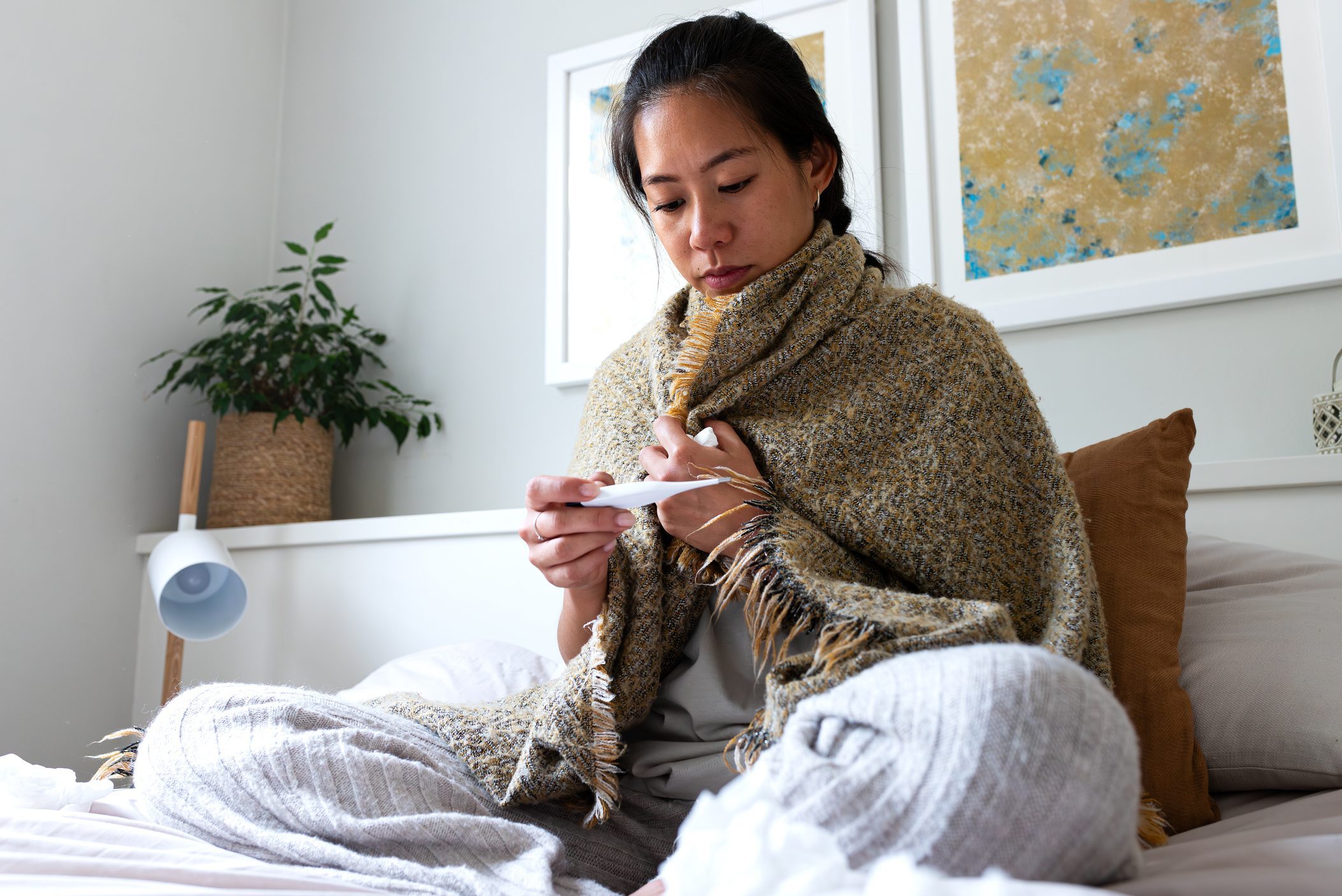 Chinese woman having the flu checking temperature with digital thermometer.