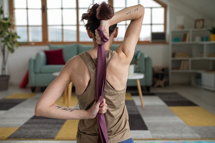 Woman using a resistance band to do yoga at home