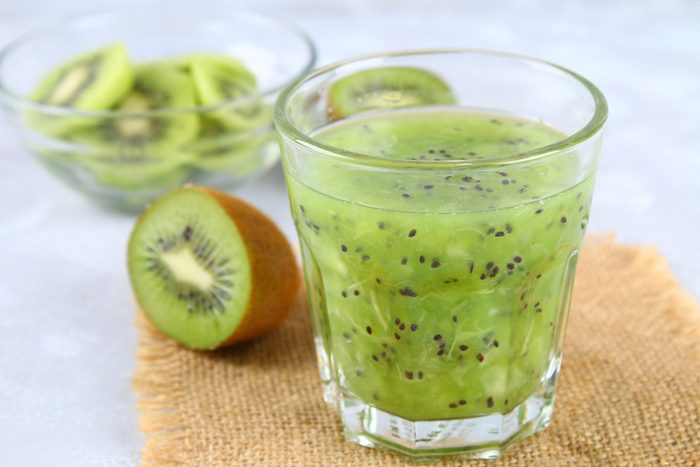 Sliced kiwi and smoothie slices in a glass on a gray table. Healthy food.