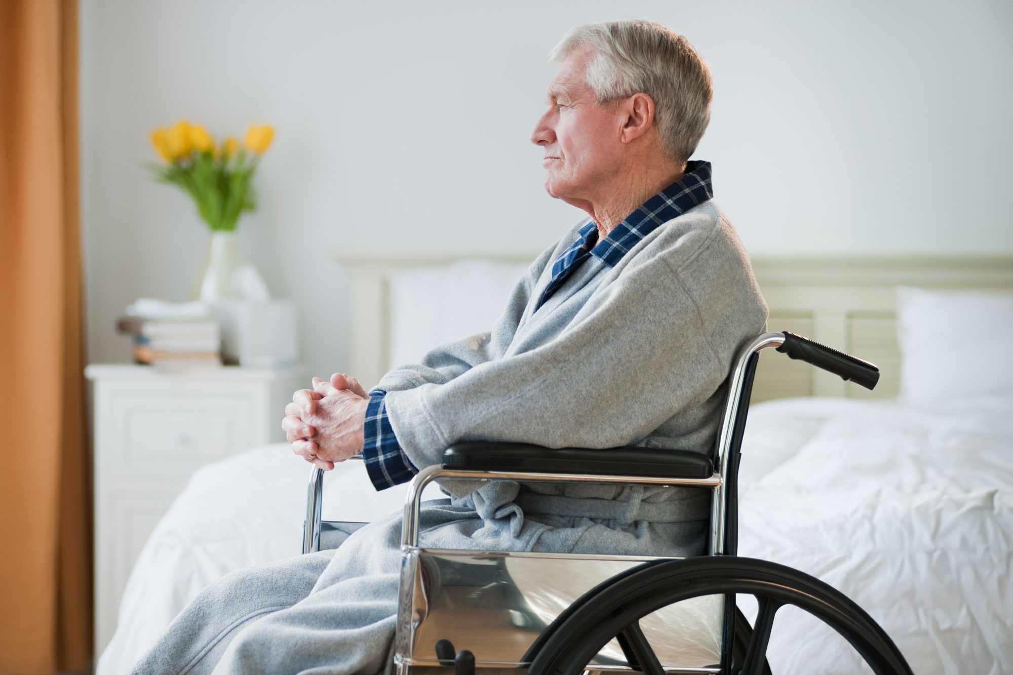 Senior Man In Wheelchair Looking Out Window