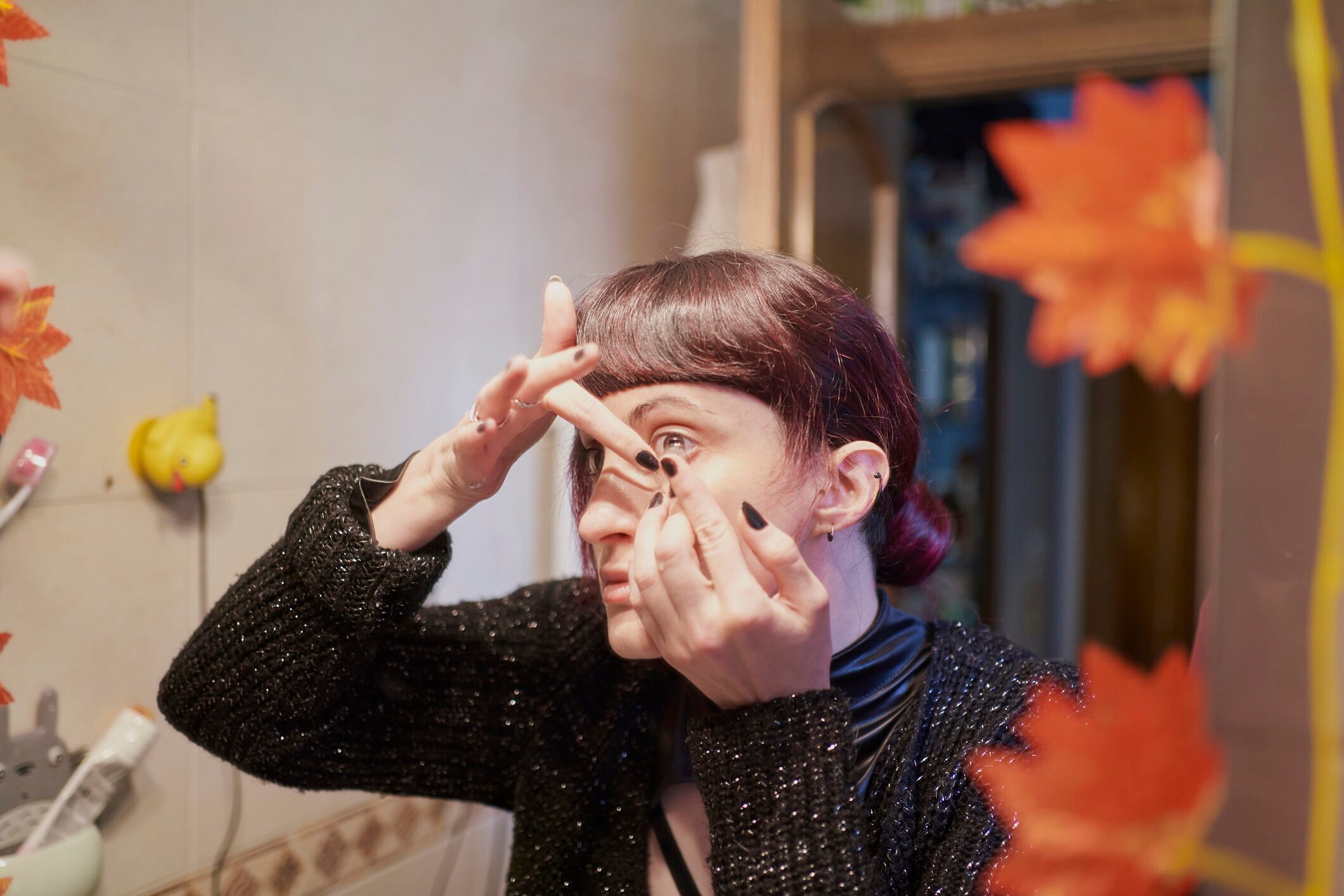 Close Up Of Young Woman In Her Bedroom Inserting Contact Lens For Halloween Costume