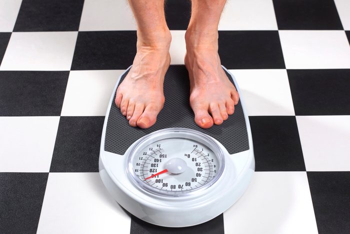 Overweight Man Standing on Bathroom Scales