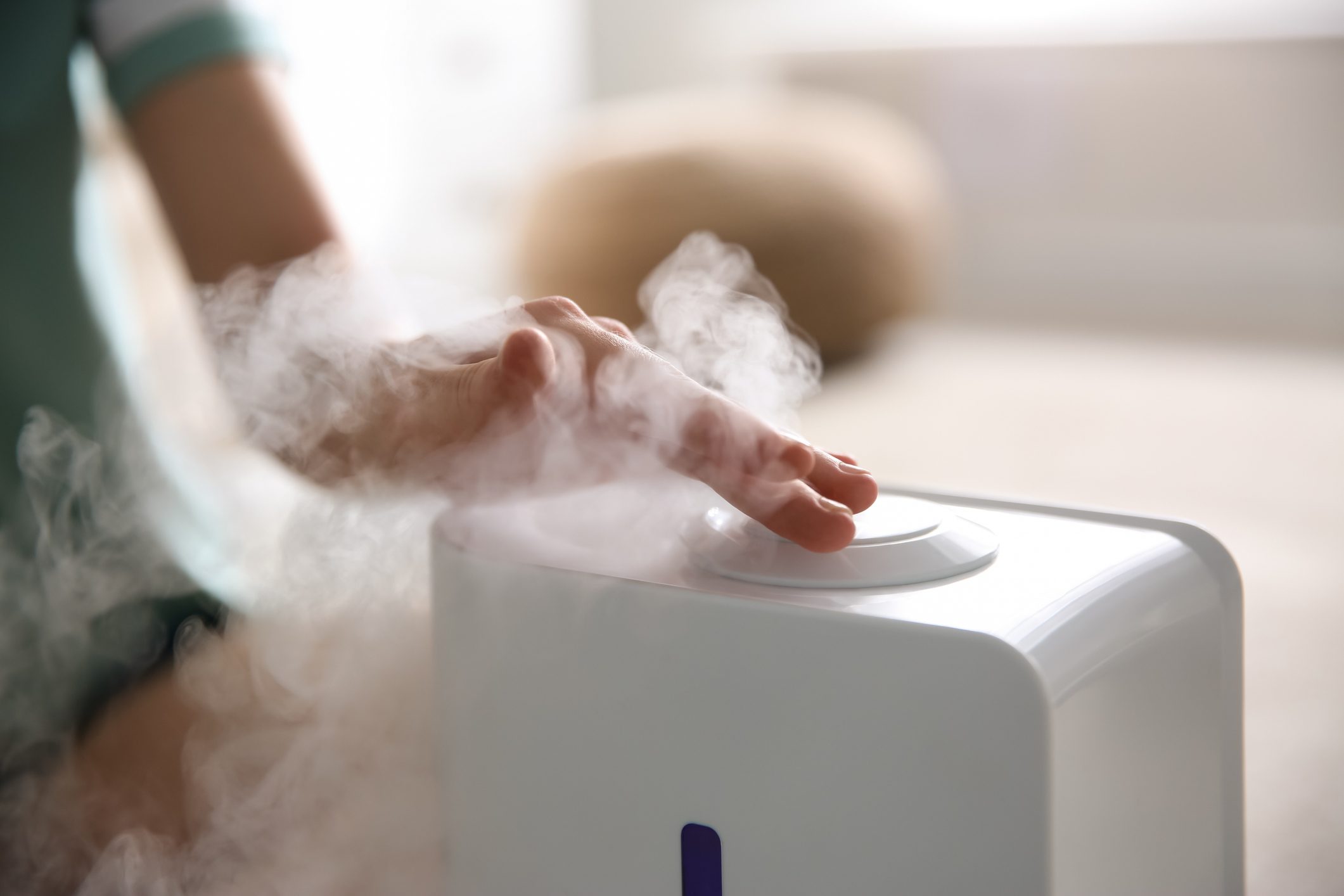 Woman using modern air humidifier at home, closeup