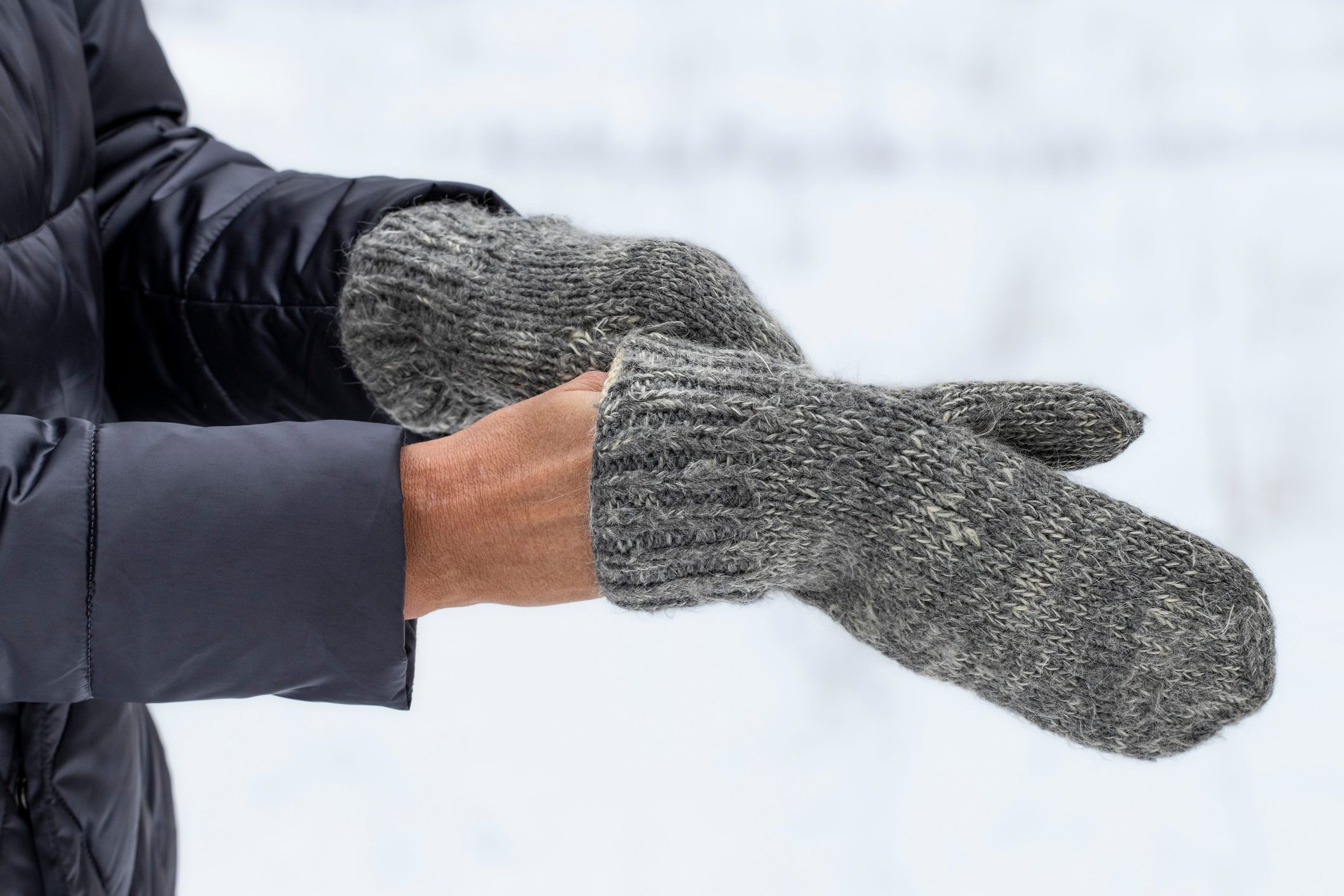 Knitted winter mittens.Warm gray mittens in women's hands.Warm clothes for walking outside in the cold season.