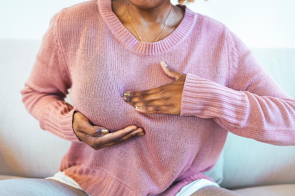 What Is A Breast Cancer Rash? Woman in pain holding her breast